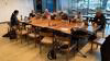 Contributors gathered at a table with laptops with a window to NYC waterfront behind them.